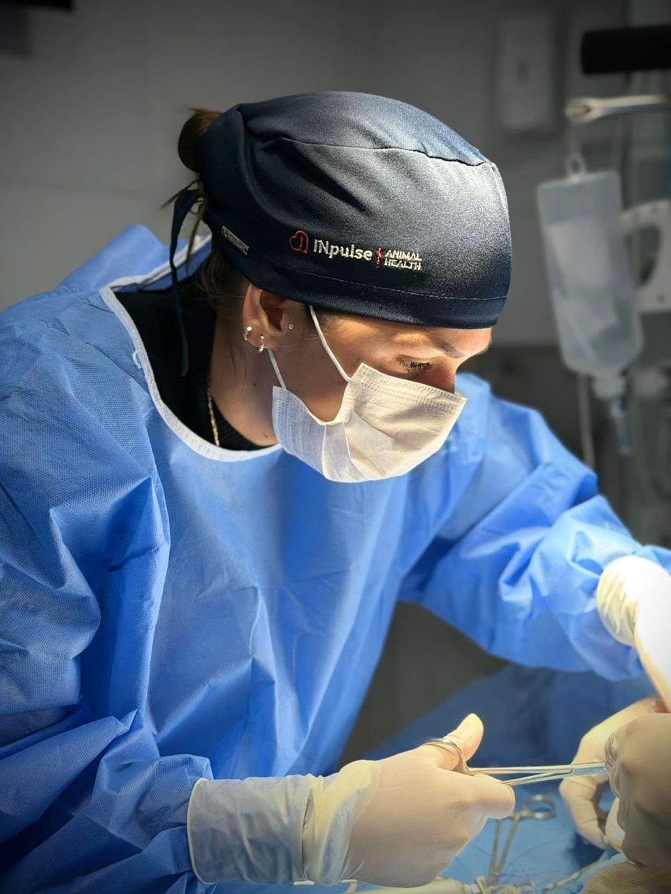 Médica veterinária da Upa Pets, de touca e avental cirúrgico, concentrada durante uma cirurgia